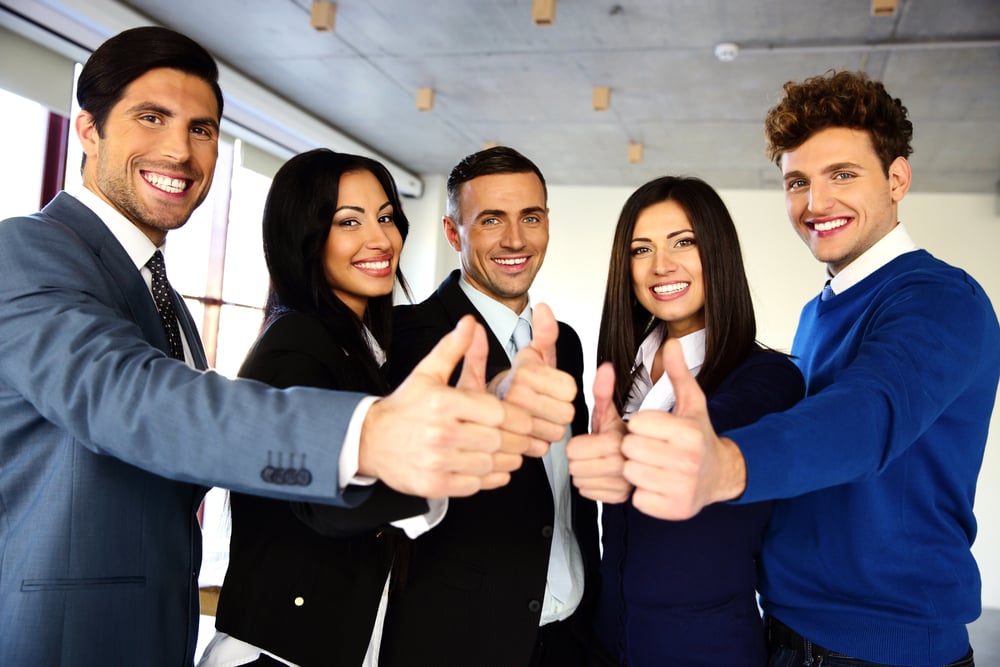 Cheerful young business team with thumbs up sign