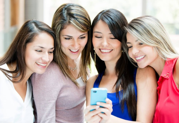 Group of girls looking at a cell phone_seo-opt