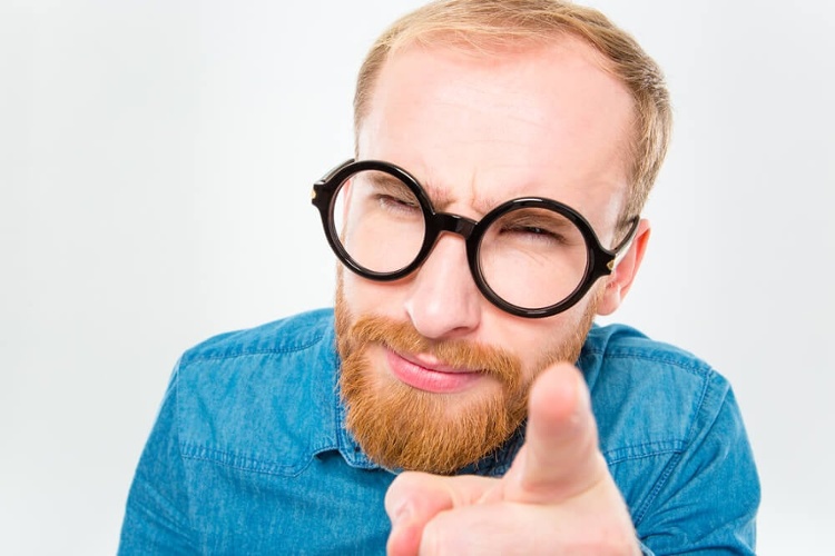 Portrait of suspicious young bearded man in funny round glasses pointing on you isolated over white background_seo-opt-1