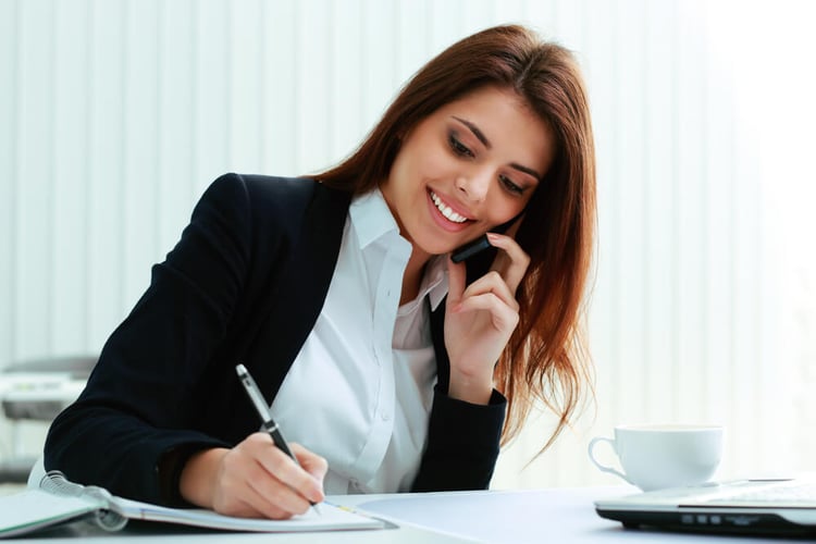 Young happy businesswoman talking on the phone and writing notes in office_seo-opt