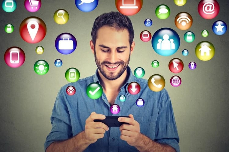 communication technology mobile phone high tech concept. Happy man using texting on smartphone social media application icons flying out of cellphone isolated grey wall background. 4g data plan-1_seo-opt