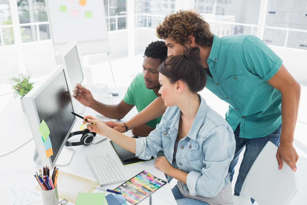 Side view of three artists working on computer at the office