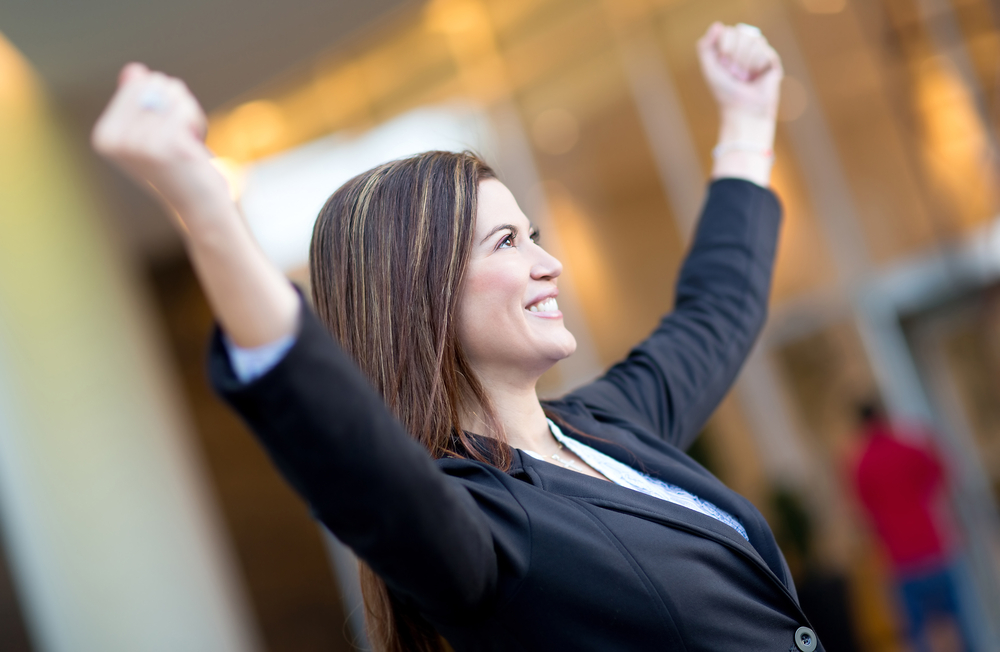 Successful business woman with arms up celebrating